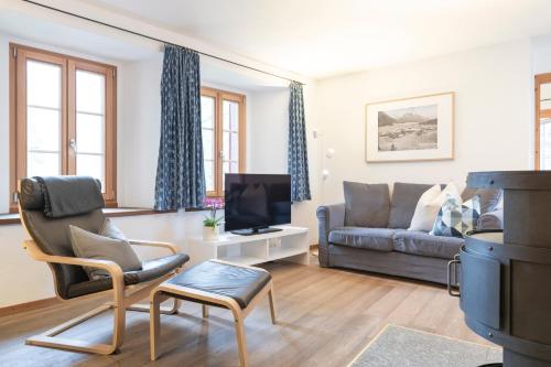 a living room with a couch and a tv at Chesa Michel in Bever