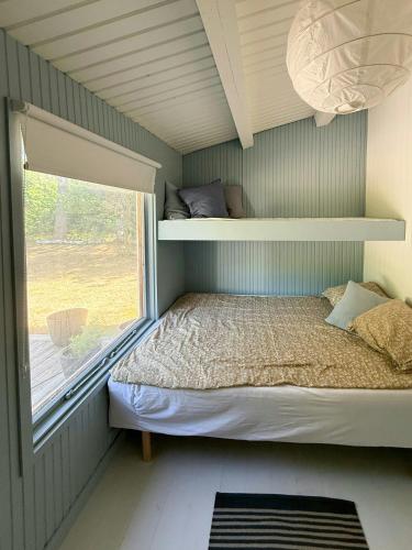 una piccola camera da letto con un letto e una finestra di Wooden Cottage Near The Beach In Odsherred ad Asnæs