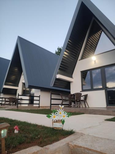 a house with a black roof and some tables and chairs at Bungalows Panorama Hills in Pluzine