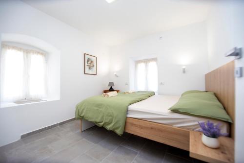 Charming Apartment in The Old Town في بودفا: غرفة نوم بجدران بيضاء وسرير بملاءات خضراء