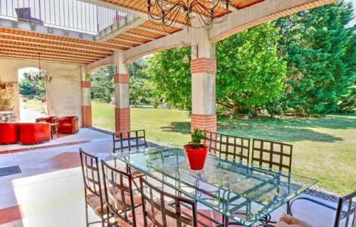 a patio with a glass table and chairs at Authentique Maison Campagne in Montredon-Labessonnié