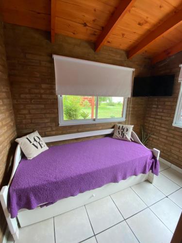 a bedroom with a purple bed with a window at Lo de Lito in Sierra de la Ventana