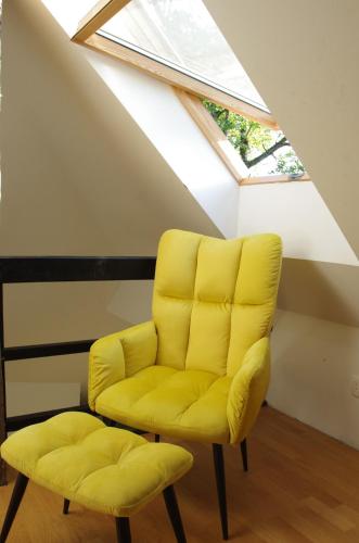 a yellow chair and stool in a room with a skylight at Hiška na skalci, The House on the Rock in Krka
