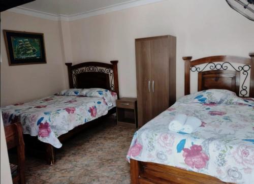 a bedroom with two beds and a dresser at Hotel San Isidro in Pisco