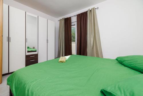 ein Schlafzimmer mit einem grünen Bett und einem Fenster in der Unterkunft Apartments Toni in Banjol