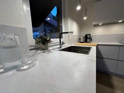 a white kitchen with a sink and a window at FachWerkPerle am Alfsee in Rieste