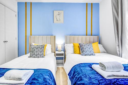 two beds in a room with blue walls at Wimbledon 3Bath Sleeps7 AELTC in London