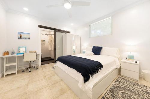a white bedroom with a bed and a desk at Island Gardens Family Escape, Pool & Car included in Nassau