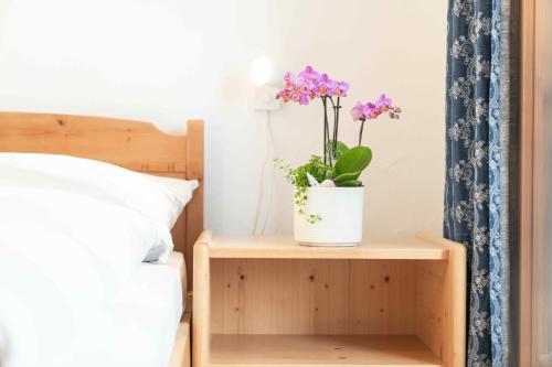 a plant on a night stand next to a bed at Chesa Michel in Bever