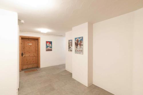 a hallway with white walls and a door at Chesa Michel in Bever