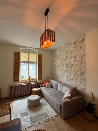 a living room with a couch and a chandelier at Apartament Zielona Kamienica in Koszalin