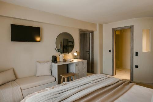 a bedroom with a bed and a couch and a mirror at Cássia Suite in Kefalonia with Balcony Nomāde Agora in Lixouri