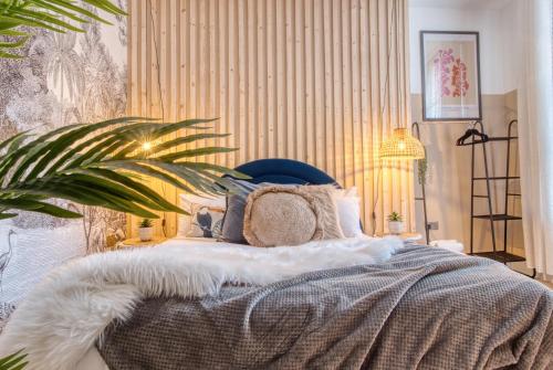 a bedroom with a bed with a blanket and a plant at London Queen's Park - hot tub, cinema, games in London