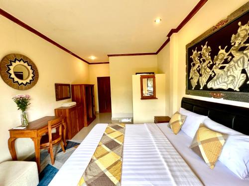 a bedroom with a bed and a table and a mirror at Guesthouse Gusti Putu Oka in Ubud