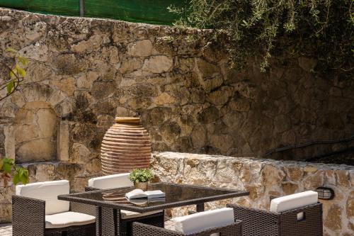 a table and chairs with a vase on a stone wall at Theros Retreat in Spartia