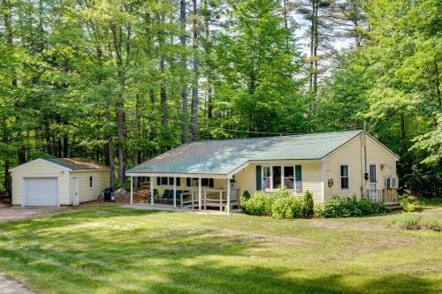 a white house with a garage in the middle of a yard at Outdoor Exploration Quaint North Conway Cottage! in North Conway