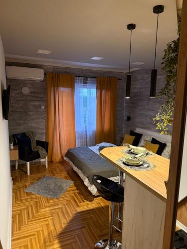 a room with a bed and a kitchen with a table at Maslačak Subotica in Subotica
