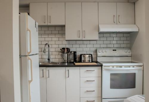 a kitchen with white cabinets and white appliances at Douce Evasion in Rouyn