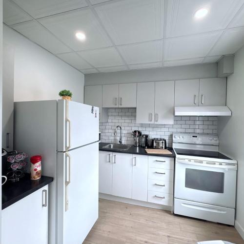 a kitchen with white cabinets and a white refrigerator at Douce Evasion in Rouyn