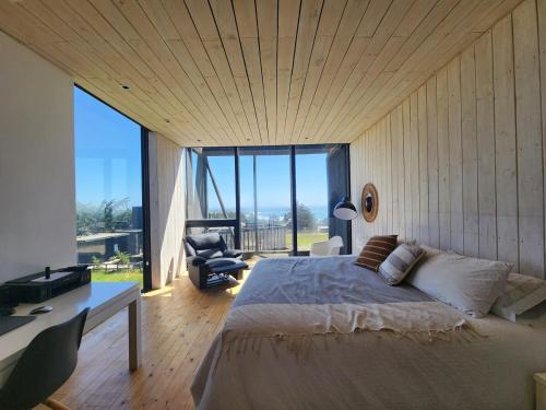 a bedroom with a bed and a desk and a large window at Punta de Lobos Black House in Pichilemu