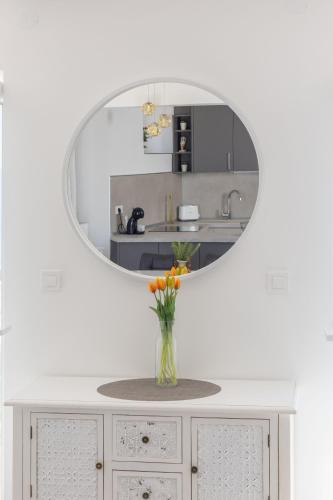 a vase of flowers on a cabinet with a mirror at Apartments Amfora 2 in Podgora