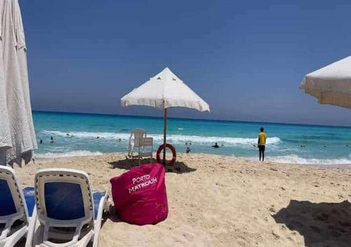 two chairs and an umbrella on a beach at شاليهات بورتو مطروح فيو بحر Porto Matrouh Sea View Families Only in Marsa Matruh