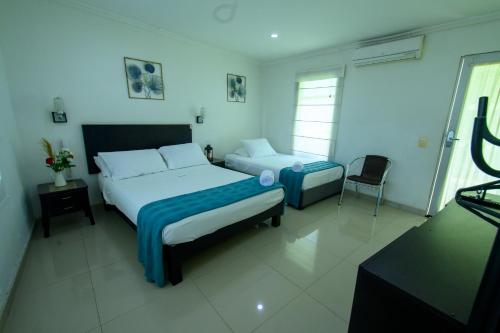 a bedroom with two beds and a chair in it at Hotel Villeta Suite in Villeta