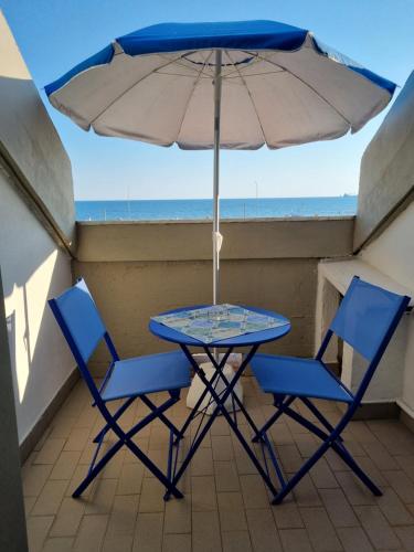 - une table avec deux chaises et un parasol sur le balcon dans l'établissement A un passo dal mare - Vista mare, à Marina di Massa