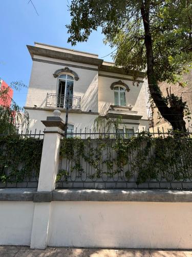 a white house with a fence in front of it at Casa Arcos Chapultepec in Mexico City