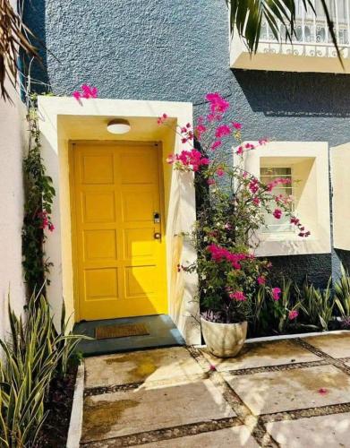 una puerta amarilla al lado de un edificio con flores en Casas Costa Azul, en Acapulco