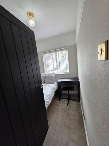 a bedroom with a bed and a desk with a window at Stunning property with Summer house in Bescot