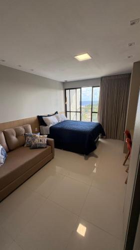 a bedroom with a couch and a bed and a window at Studio em Salvador- Vista Mar in Salvador