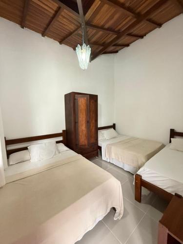 a bedroom with two beds and a chandelier at Casa frente ao mar/pé na areia no Indaiá até 18 pessoas in Bertioga