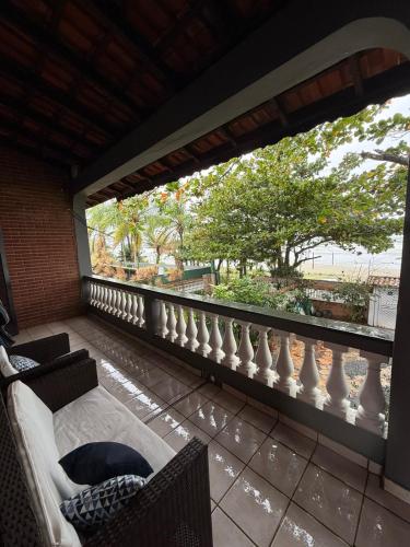 a balcony with chairs and a view of a tree at Casa frente ao mar/pé na areia no Indaiá até 18 pessoas in Bertioga