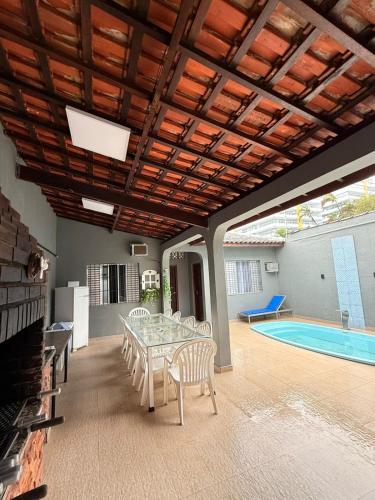 a patio with a table and chairs and a swimming pool at Casa frente ao mar/pé na areia no Indaiá até 18 pessoas in Bertioga