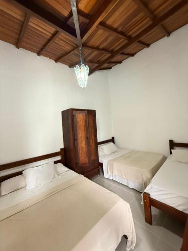 a bedroom with two beds and a chandelier at Casa frente ao mar/pé na areia no Indaiá até 18 pessoas in Bertioga