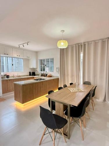 a kitchen and dining room with a wooden table and chairs at Casa frente ao mar/pé na areia no Indaiá até 18 pessoas in Bertioga