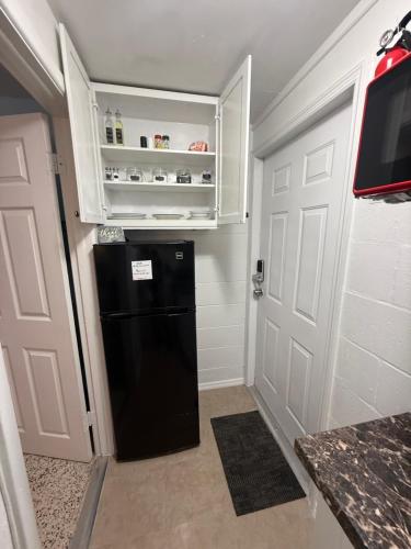 a small black refrigerator in a room with a door at Studio Yunet in Bradenton