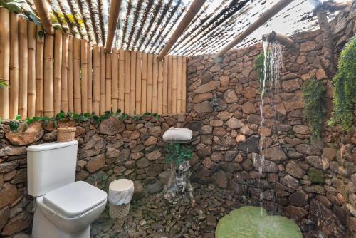 a bathroom with a toilet and a stone wall at El Refugio de Las Vegas in Valsequillo