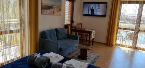 a living room with a blue chair and a tv at Villa Kapitańska in Kołobrzeg