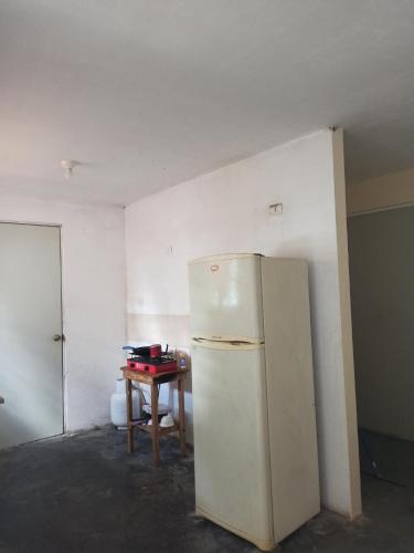 a white refrigerator in a room with a table at Casita a 10 min del aeropuerto Internacional de Monterrey in Pesquería