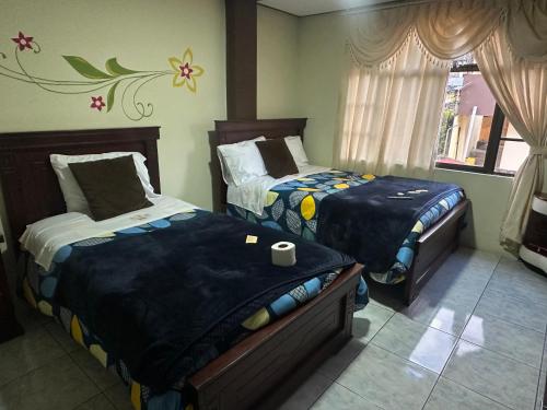 a bedroom with two beds and a window at Hotel Casa Santa Lucía in Baños