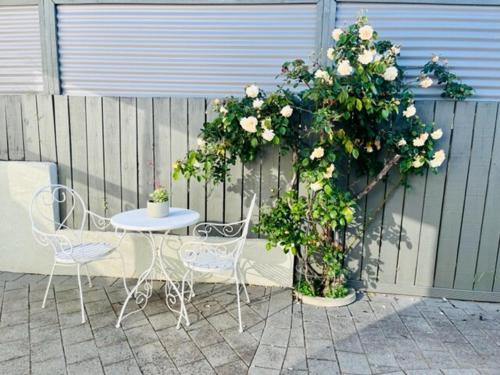 a table and chairs next to a fence with flowers at Webber by the Sea in Paraparaumu Beach