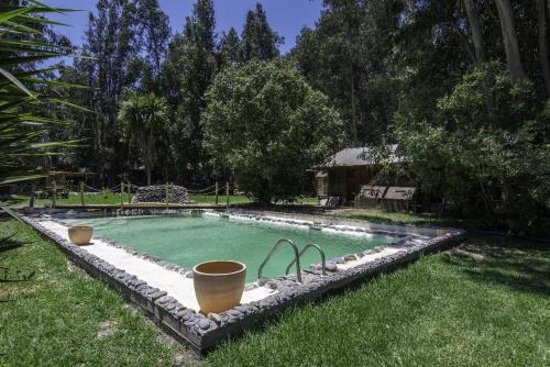 a swimming pool in the grass with two buckets at Bosques del Paico in El Monte
