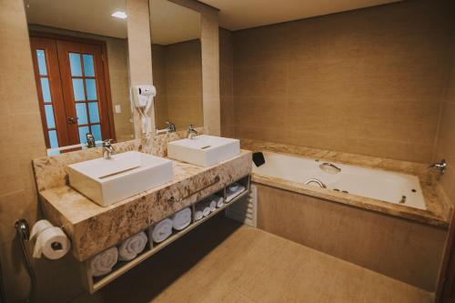 a bathroom with two sinks and a bath tub at Hotel Amantykir in Itajubá