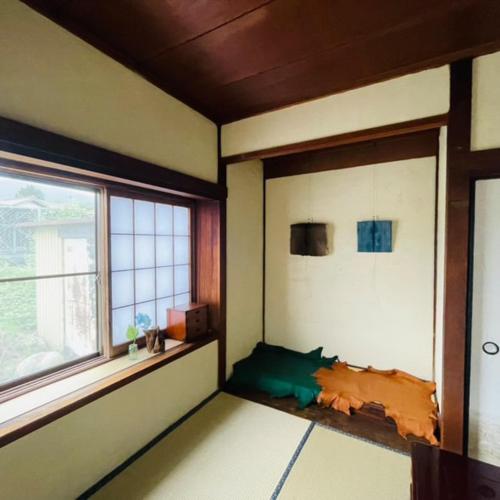 a room with a window and a bed in it at Guest House KANOKO in Nakatsugawa