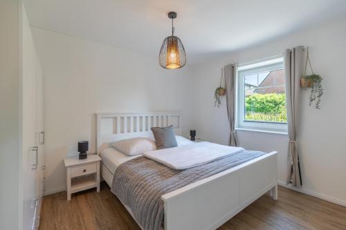 Un dormitorio blanco con una cama y una ventana. en Ferienhaus Norderreihe, en Ostenfeld