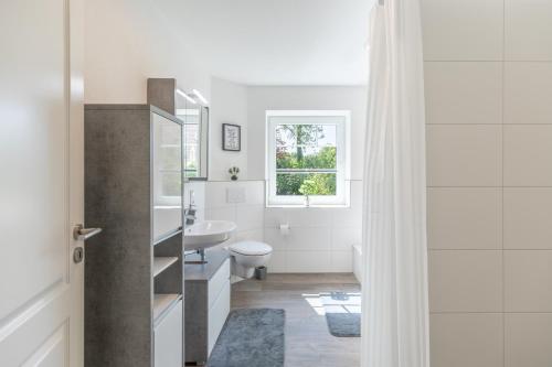 Un baño blanco con lavabo e inodoro. en Ferienhaus Norderreihe, en Ostenfeld