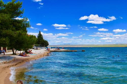 a beach with people sitting on the sand and the water at Apartments by the sea Bilice, Krka - 23875 in Šibenik