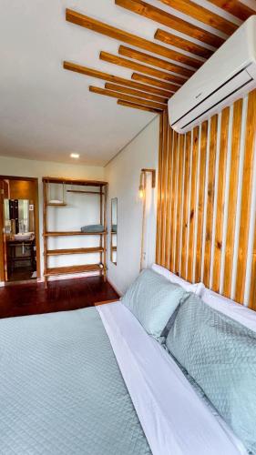 a bedroom with a white bed with a wooden wall at Docas da Lapa in Santana do Riacho